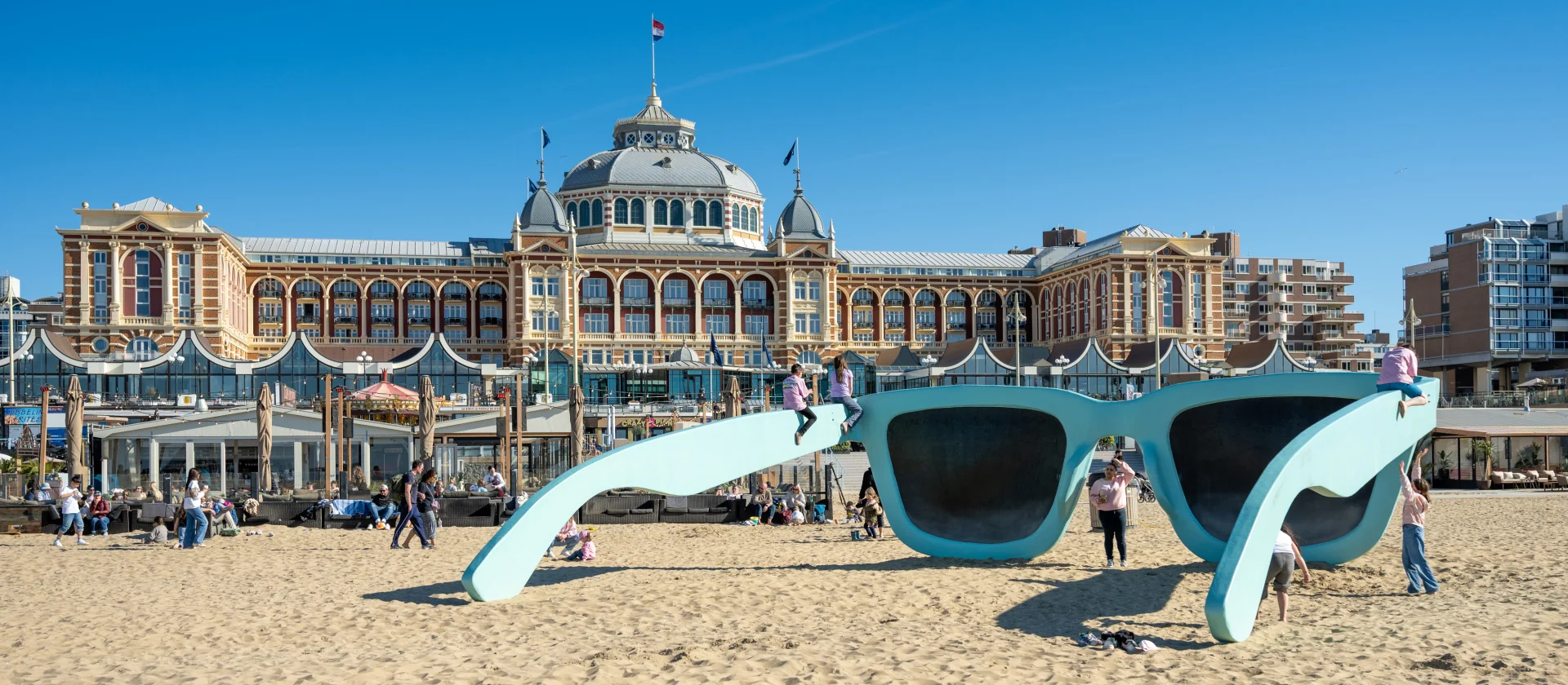 Menschen spielen bei einer riesigen blauen Sonnenbrille am Strand